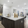 open concept layout with kitchen with large island, brown wood tone cabinets, white stone counters, stainless steel appliances, and living area in the background